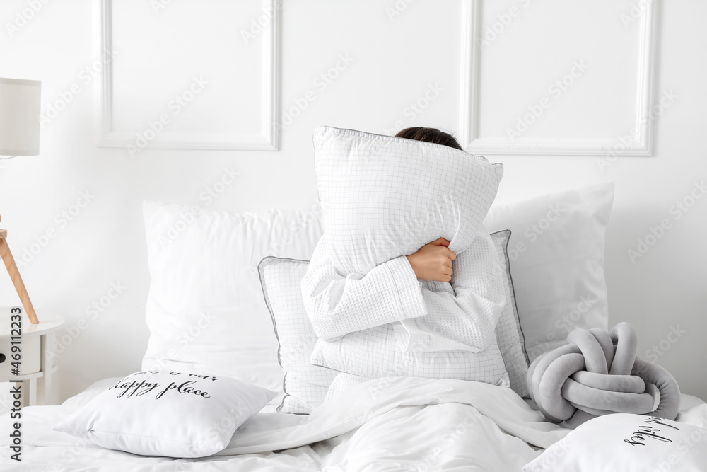Morning of young woman sitting with pillow in bed