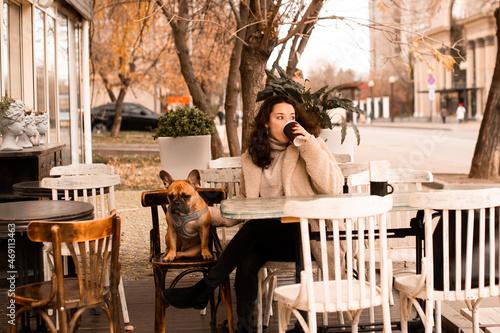 Young brunette woman with her pet french bulldog in coffee shop © Denira