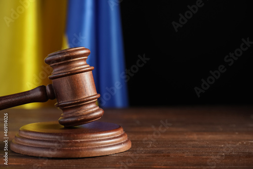 Judge's gavel on table against flag of Ukraine and dark background photo