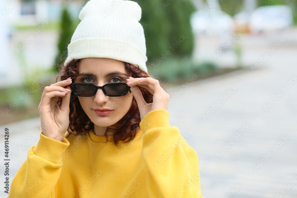 Portrait of young woman with curly hair and green eyes wearing beanie hat and sunglasses outdoors Portrait of young woman with curly hair and green eyes wearing beanie hat and sunglasses outdoors