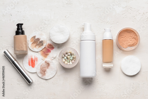 Different cosmetics and used cotton pads on light background