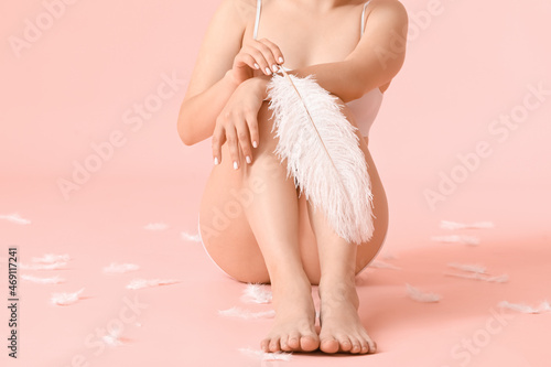 Beautiful young woman with soft feathers on color background. Epilation concept photo