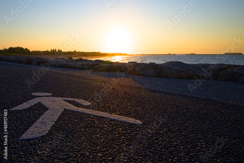 Peinture de pièton au sol devant un coucher de soleil sur la mer, et sur la rade de Cherbourg en Normandie