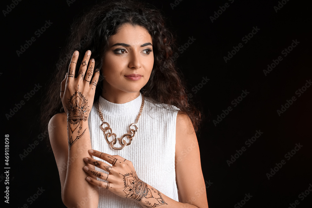 Beautiful Indian woman with henna tattoo on dark background