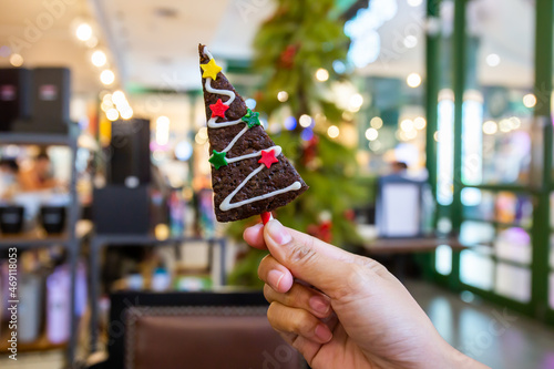 A woman's hand holds a Christmas chocolate brownie with stars to celebrate the new year.