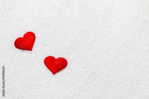 Valentine's Day concept. Two red hearts on white snow.