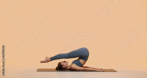 Yogi girl practice yoga showing Plow Pose or Halasana in studio. Pilates workout for healthy spine and woman wellness photo
