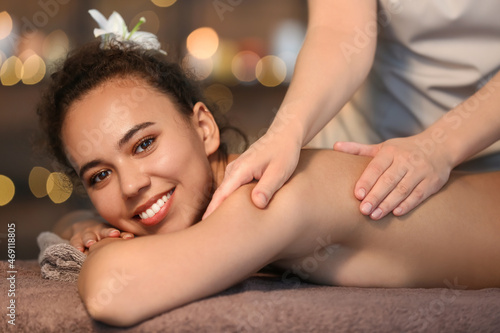 Beautiful African-American woman getting massage by therapist in spa salon, closeup