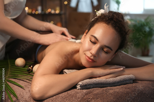 Beautiful African-American woman getting massage by therapist in spa salon
