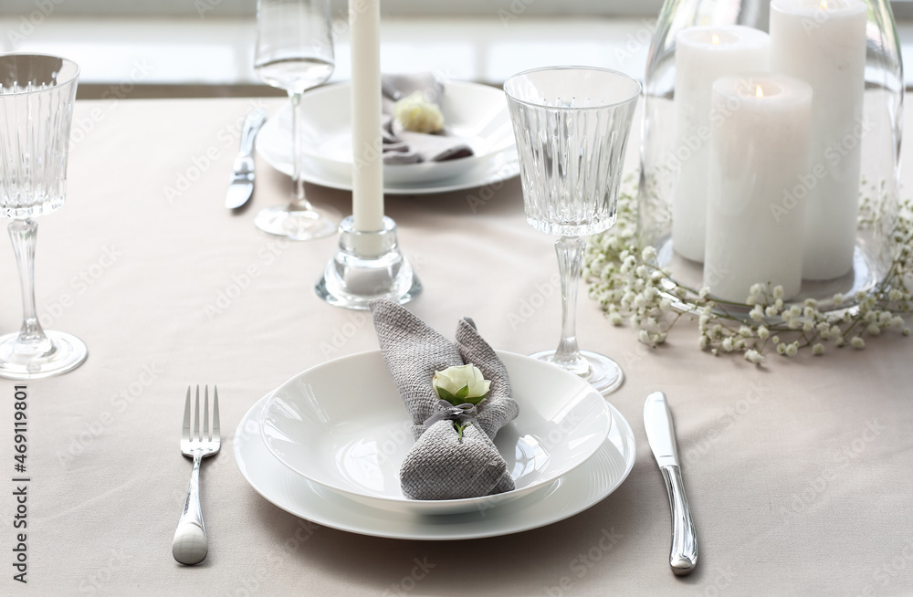 Fototapeta premium Elegant dining table setting with white candles and floral decor for special occasions and celebrations