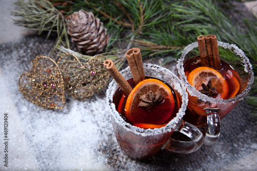 Christmas hot mulled wine with a slice of orange and spices. A glass cup with a hot traditional drink on a snowy background in festive decorations. Evening mood and decoration 