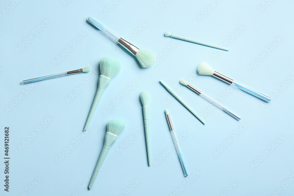 Set of beautiful makeup brushes on blue background Set of beautiful makeup brushes on blue background