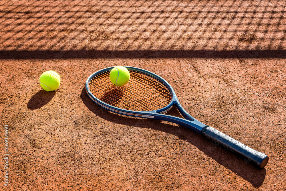 Tennis racket and new tennis ball on a Red clay court.