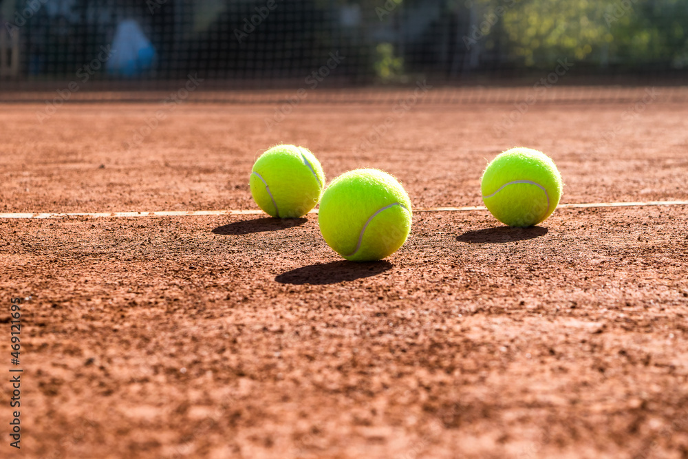 Close up of three tennis balls on a tennis clay court. Red clay court.
