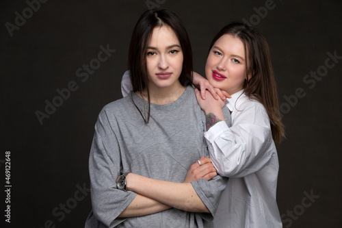 Two beautiful girls-friends on a dark background.