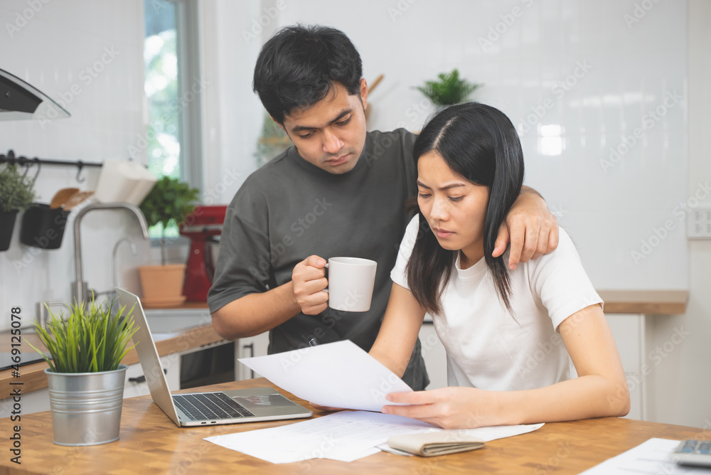Stressed Asian couple reading notice mail from the bank about unpaid house mortgage Stressed Asian couple reading notice mail from the bank about unpaid house mortgage