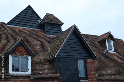 Old English roof with roof tiles and wooden details and windows
