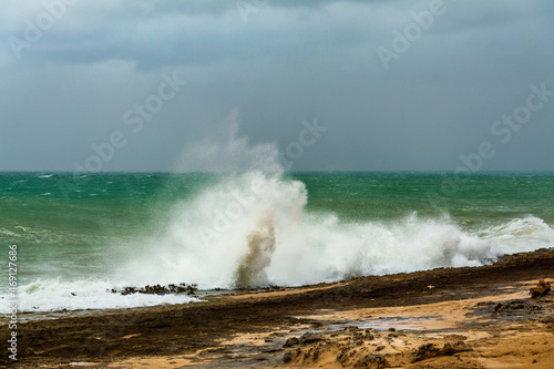 angry turquoise green color massive rip curl of a waves as it barrel rolls along the ocean. wild waves pound the coastline of chabahar in stormy day with cloudy sky close to coastline, oman sea