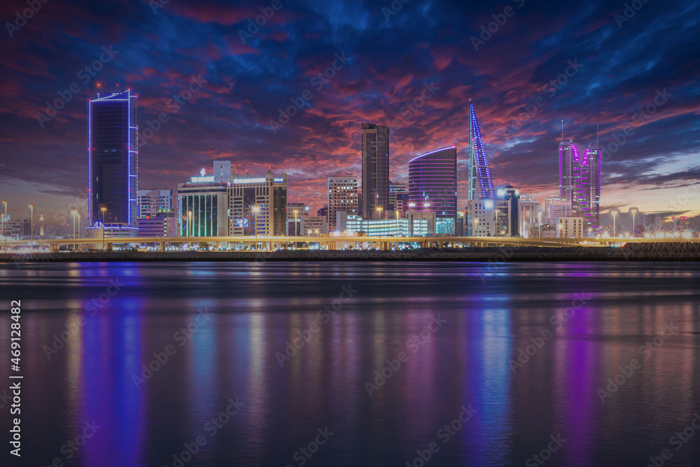 The sun set modern city skyline with neon lights and reflection in the water. Manama, the Capital of Bahrain, Middle East