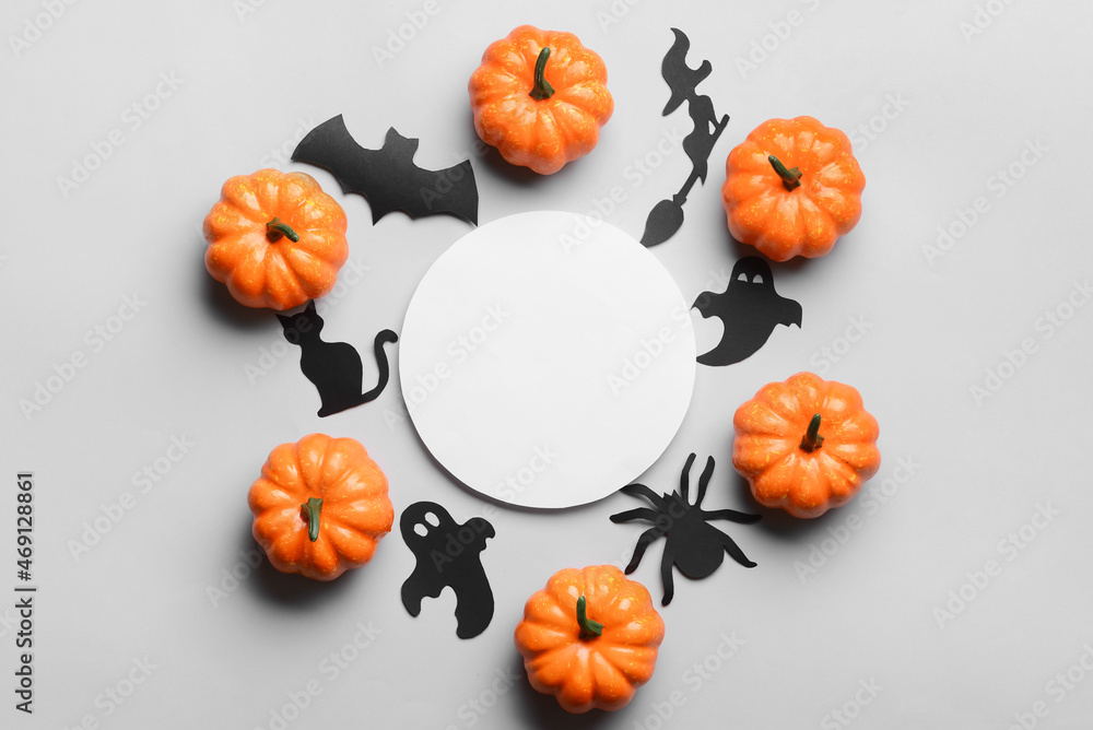 Fototapeta premium Blank paper sheet with Halloween decor and pumpkins on light background