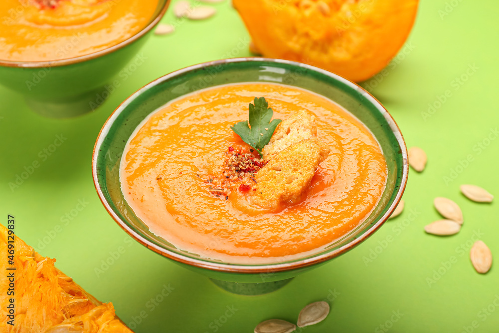 Bowl with delicious pumpkin cream soup on green background, closeup Bowl with delicious pumpkin cream soup on green background, closeup