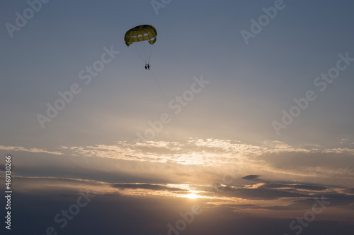 two tourists parasailing over the sea during sunset
