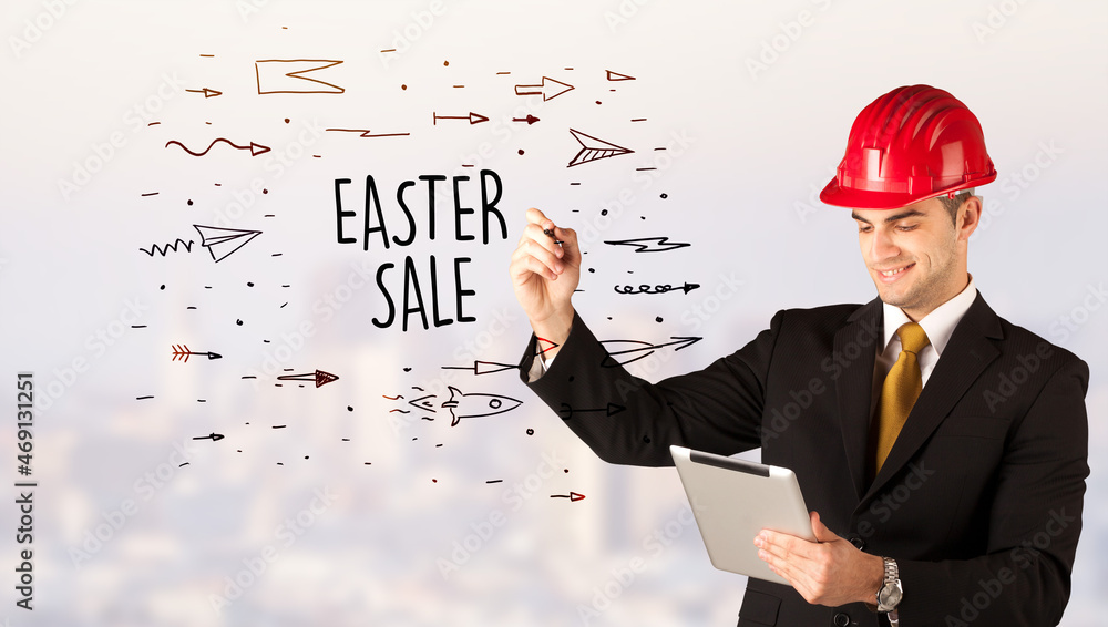 Young businessman with helmet drawing sale sign Young businessman with helmet drawing sale sign