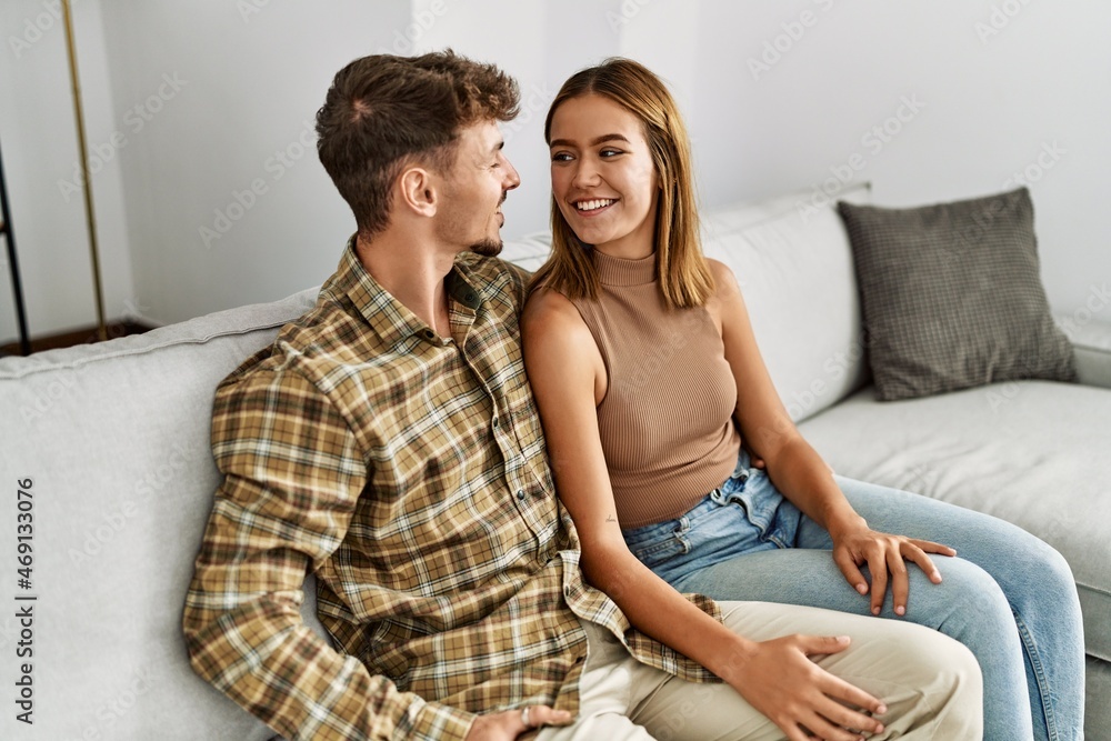 Young hispanic couple smiling happy and hugging sitting on the sofa at home. Young hispanic couple smiling happy and hugging sitting on the sofa at home.