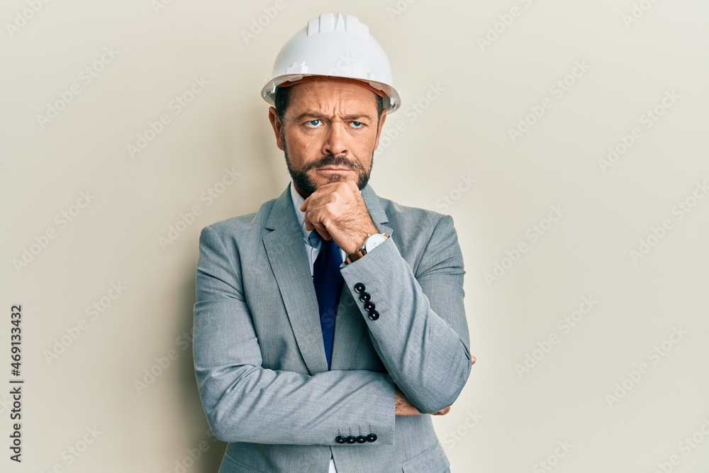 Middle age man wearing architect hardhat thinking concentrated about doubt with finger on chin and looking up wondering Middle age man wearing architect hardhat thinking concentrated about doubt with finger on chin and looking up wondering