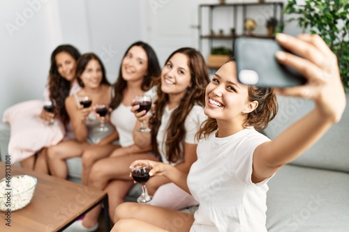 Group of young hispanic women celebrating pajamas party make selfie by the smartphone at home.