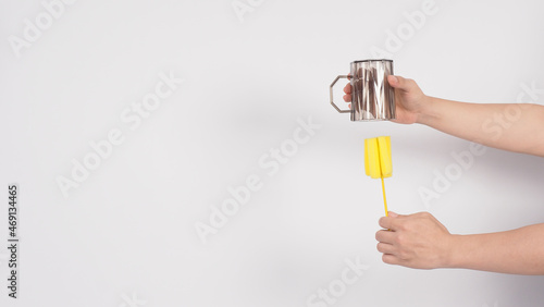 Clean and wash dish concept. Man hand washing drink glass on white background. Used drinking glass cleaning by soft yellow sponge stick. Wash cup by sponge brush. Disinfection hyginic in covid 19 era