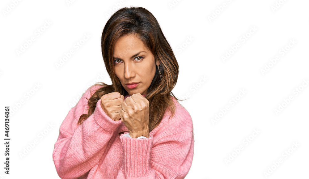 Young hispanic woman wearing casual clothes ready to fight with fist defense gesture, angry and upset face, afraid of problem Young hispanic woman wearing casual clothes ready to fight with fist defense gesture, angry and upset face, afraid of problem