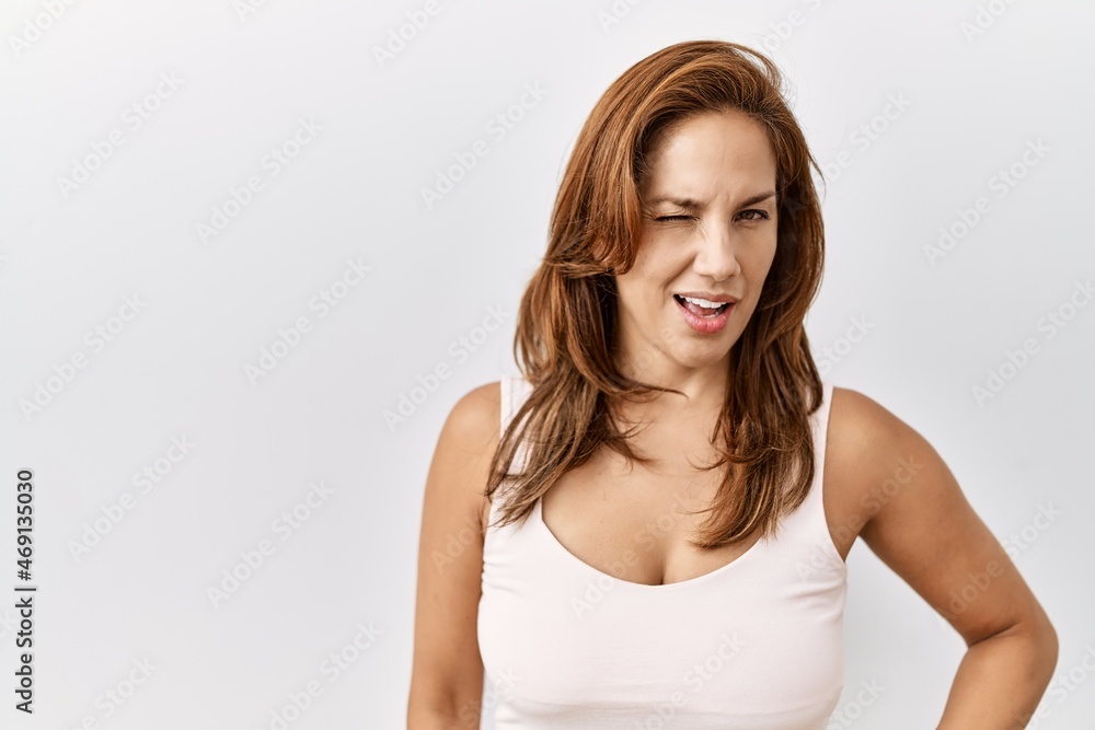 Middle age hispanic woman standing over isolated background winking looking at the camera with sexy expression, cheerful and happy face. Middle age hispanic woman standing over isolated background winking looking at the camera with sexy expression, cheerful and happy face.