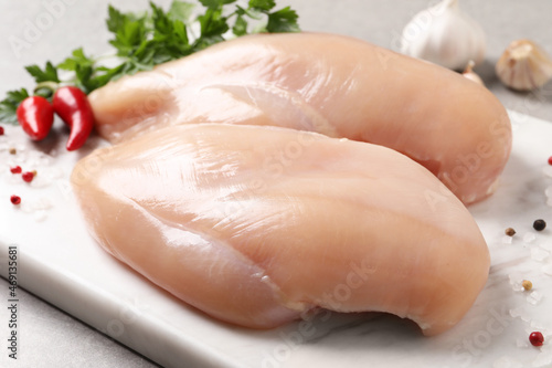 Raw chicken breasts and ingredients on light grey table, closeup