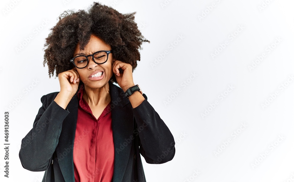 African american woman with afro hair wearing business jacket and glasses covering ears with fingers with annoyed expression for the noise of loud music. deaf concept. African american woman with afro hair wearing business jacket and glasses covering ears with fingers with annoyed expression for the noise of loud music. deaf concept.