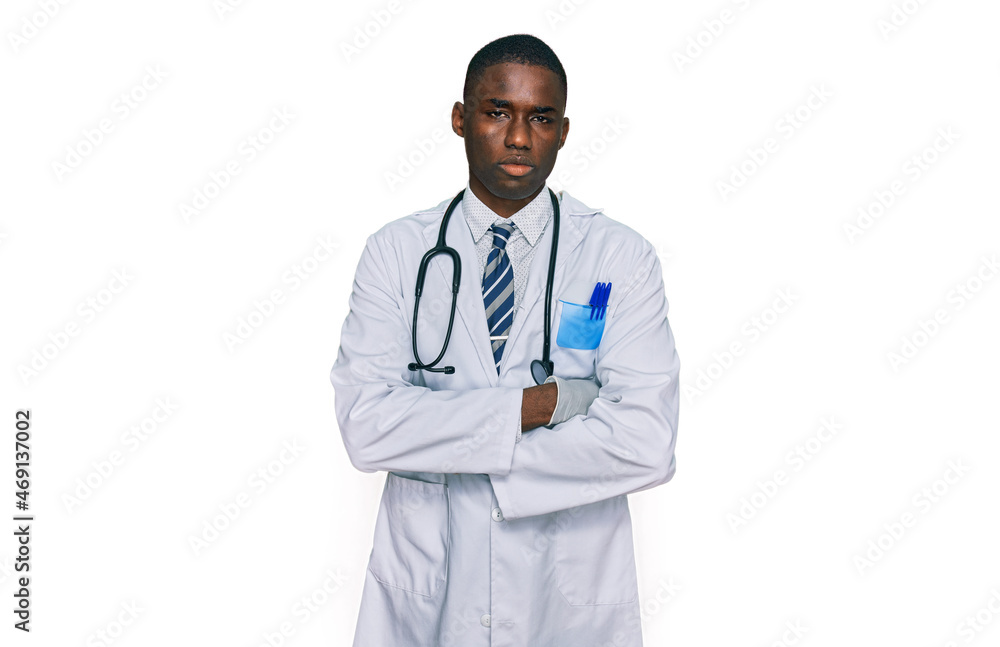 Young african american man wearing doctor uniform and stethoscope skeptic and nervous, disapproving expression on face with crossed arms. negative person. Young african american man wearing doctor uniform and stethoscope skeptic and nervous, disapproving expression on face with crossed arms. negative person.