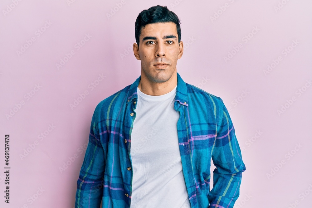 Handsome hispanic man wearing casual clothes relaxed with serious expression on face. simple and natural looking at the camera. Handsome hispanic man wearing casual clothes relaxed with serious expression on face. simple and natural looking at the camera.