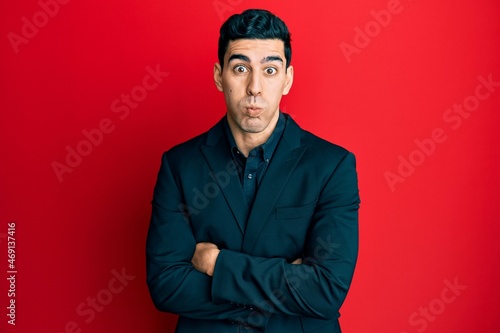 Handsome hispanic business man with arms crossed gesture puffing cheeks with funny face. mouth inflated with air, catching air. © Krakenimages.com