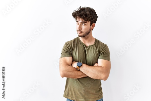 Hispanic man standing over isolated white background looking to the side with arms crossed convinced and confident