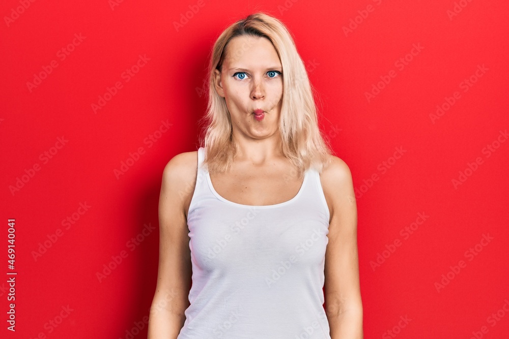 Beautiful caucasian blonde woman wearing casual white t shirt making fish face with lips, crazy and comical gesture. funny expression. Beautiful caucasian blonde woman wearing casual white t shirt making fish face with lips, crazy and comical gesture. funny expression.