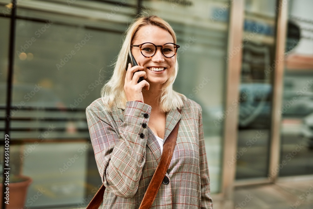 Young blonde businesswoman smiling happy talking on the smartphone at the city.
