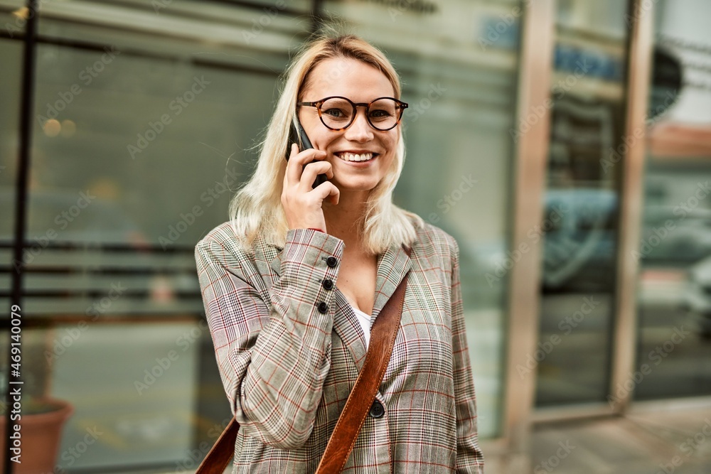 Fototapeta premium Young blonde businesswoman smiling happy talking on the smartphone at the city.