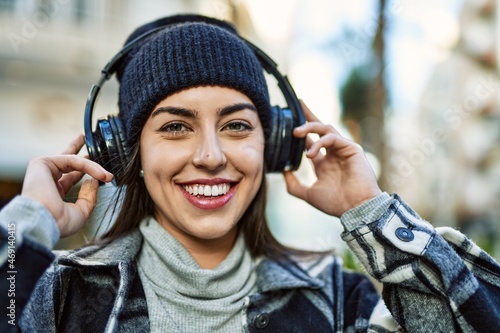 Young hispanic woman smiling happy using headphones at the city.