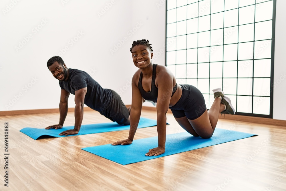 Young african american sporty couple smiling happy doing core abs exercise at sport center. Young african american sporty couple smiling happy doing core abs exercise at sport center.