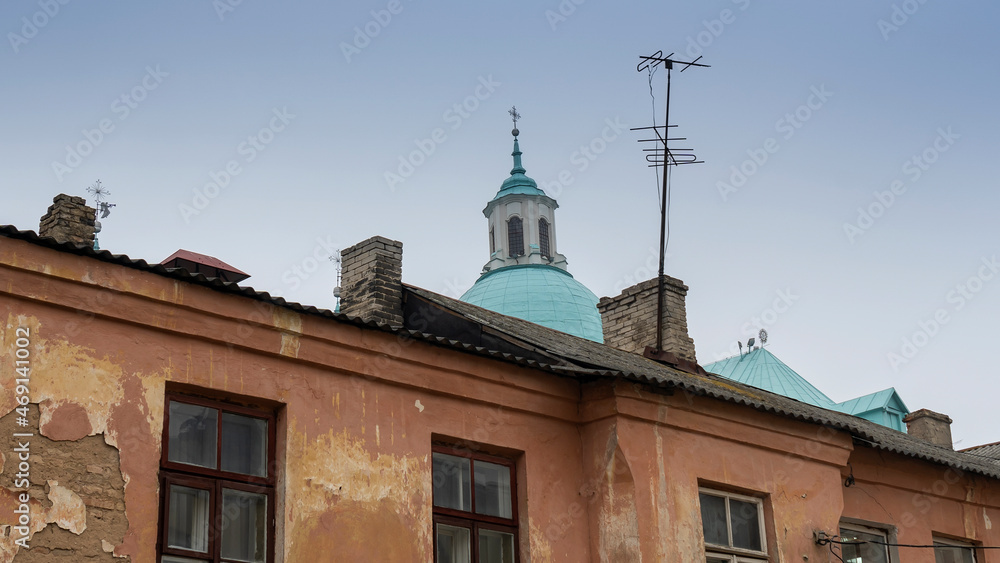 Catholic dom with cross viewed through television aerial antennae and apartment rooftops.