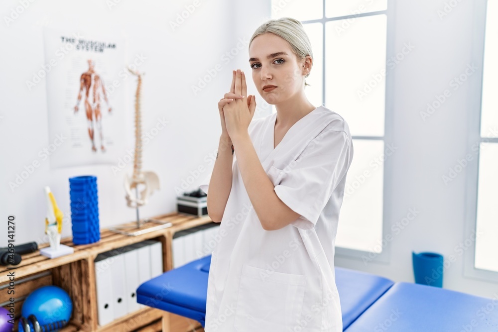 Young caucasian woman working at pain recovery clinic holding symbolic gun with hand gesture, playing killing shooting weapons, angry face Young caucasian woman working at pain recovery clinic holding symbolic gun with hand gesture, playing killing shooting weapons, angry face