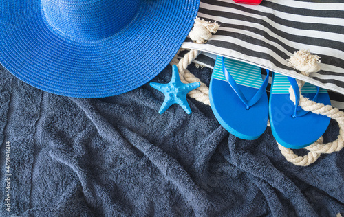 Summer beach holidays concept; Blue hat, beach bag, flip flop and blue starfish on dark blue tovel; copy space