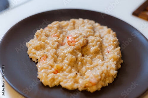 Risotto with shrimp in cream sauce on a dark plate