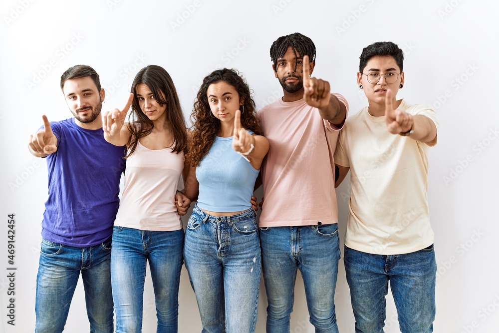 Group of young people standing together over isolated background pointing with finger up and angry expression, showing no gesture Group of young people standing together over isolated background pointing with finger up and angry expression, showing no gesture