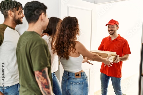 Group of people holding take away pizzas from deliveryman at home.